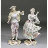 A pair of Continental porcelain figures of a young man with flute and girl dancing, 9.75ins and 9.