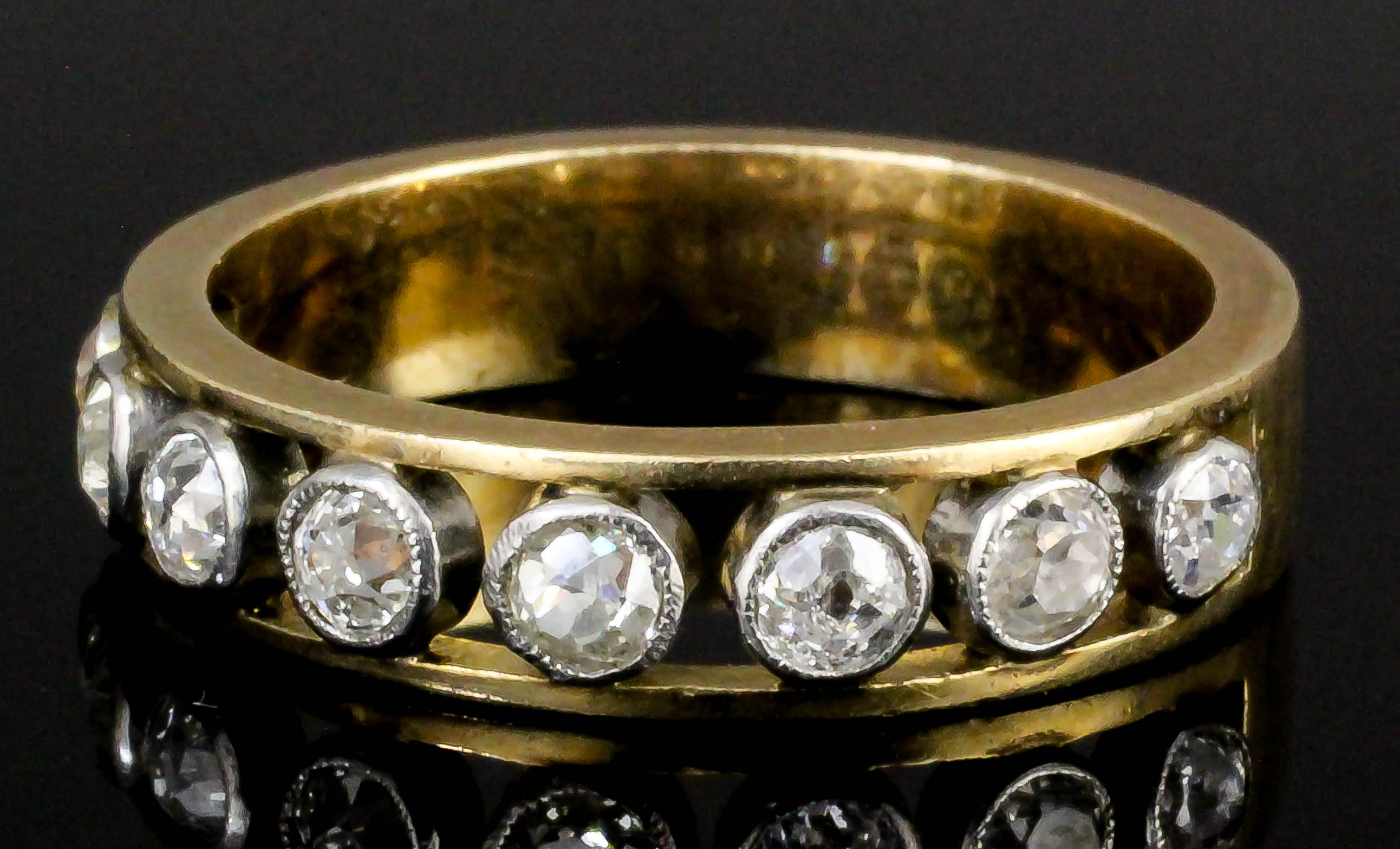 A 1920s gold coloured metal and all diamond set half hoop eternity ring, the face with eight