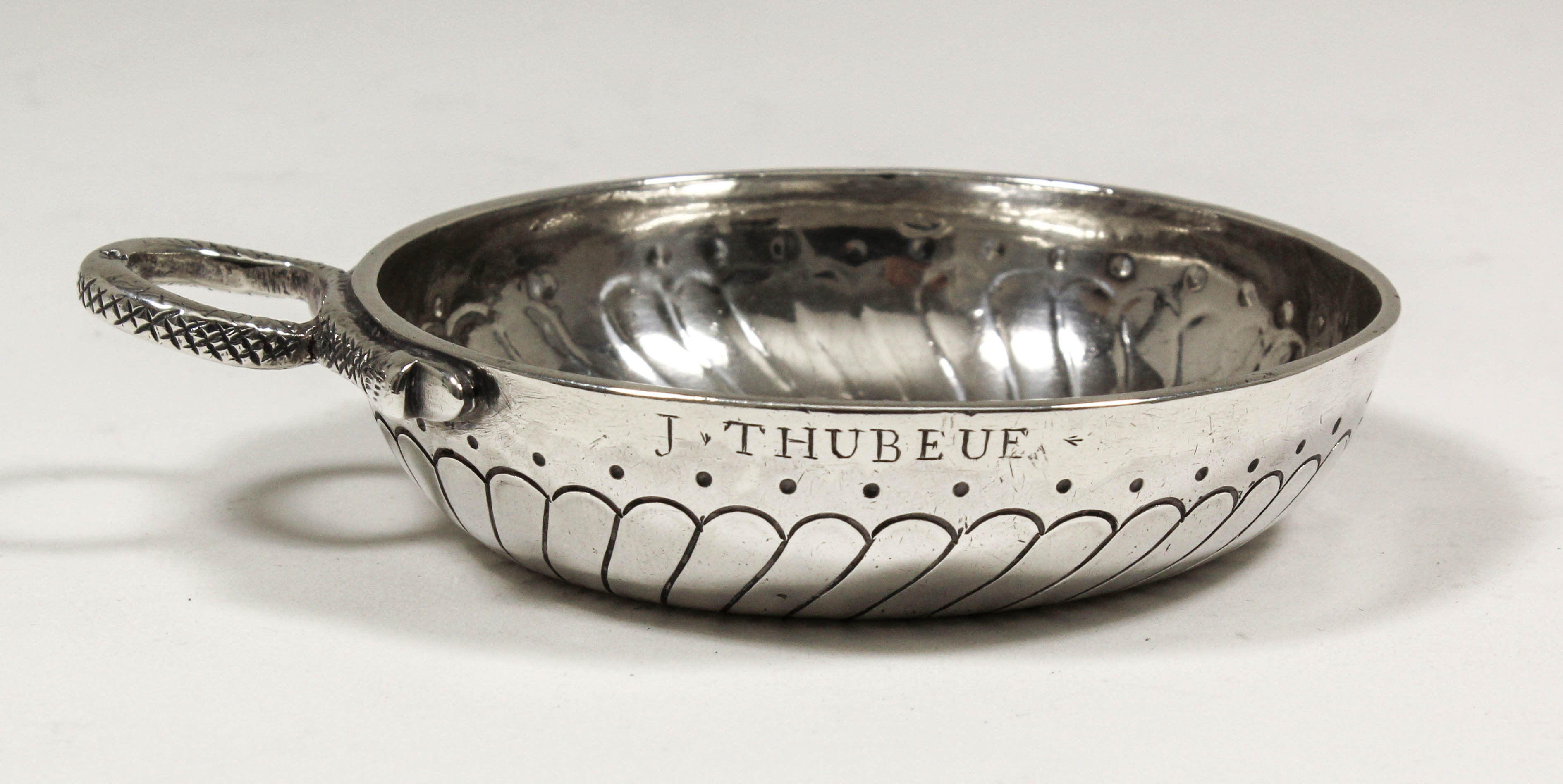 An 18th Century French silver circular taste-vin, the bowl engraved with spiral ribbed ornament