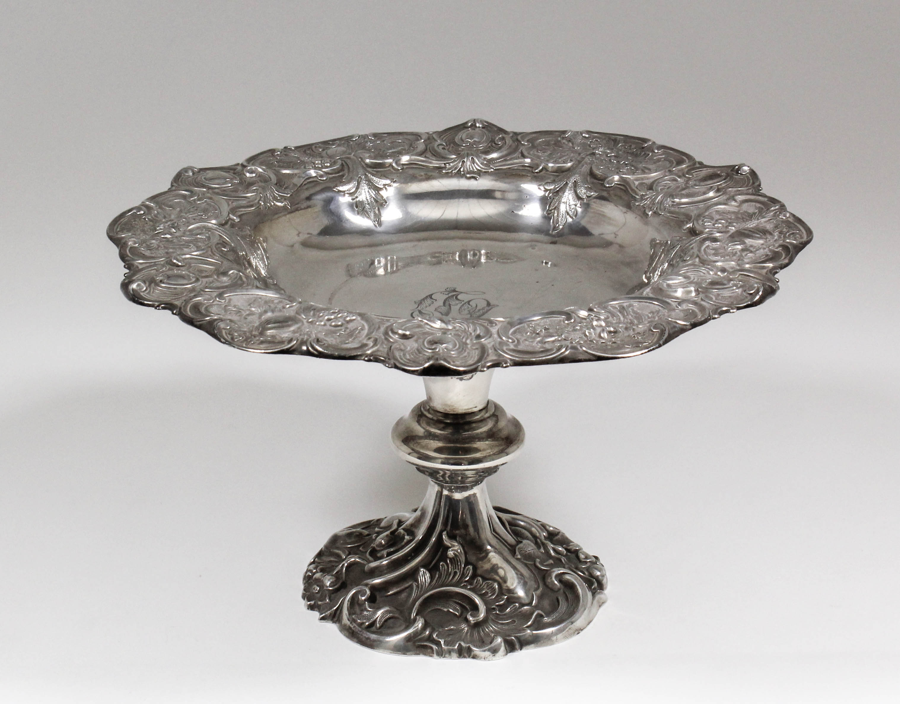 A late Victorian silver circular tazza of shaped outline, the rim cast with oval cartouche,