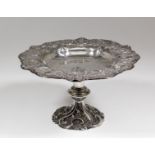 A late Victorian silver circular tazza of shaped outline, the rim cast with oval cartouche,