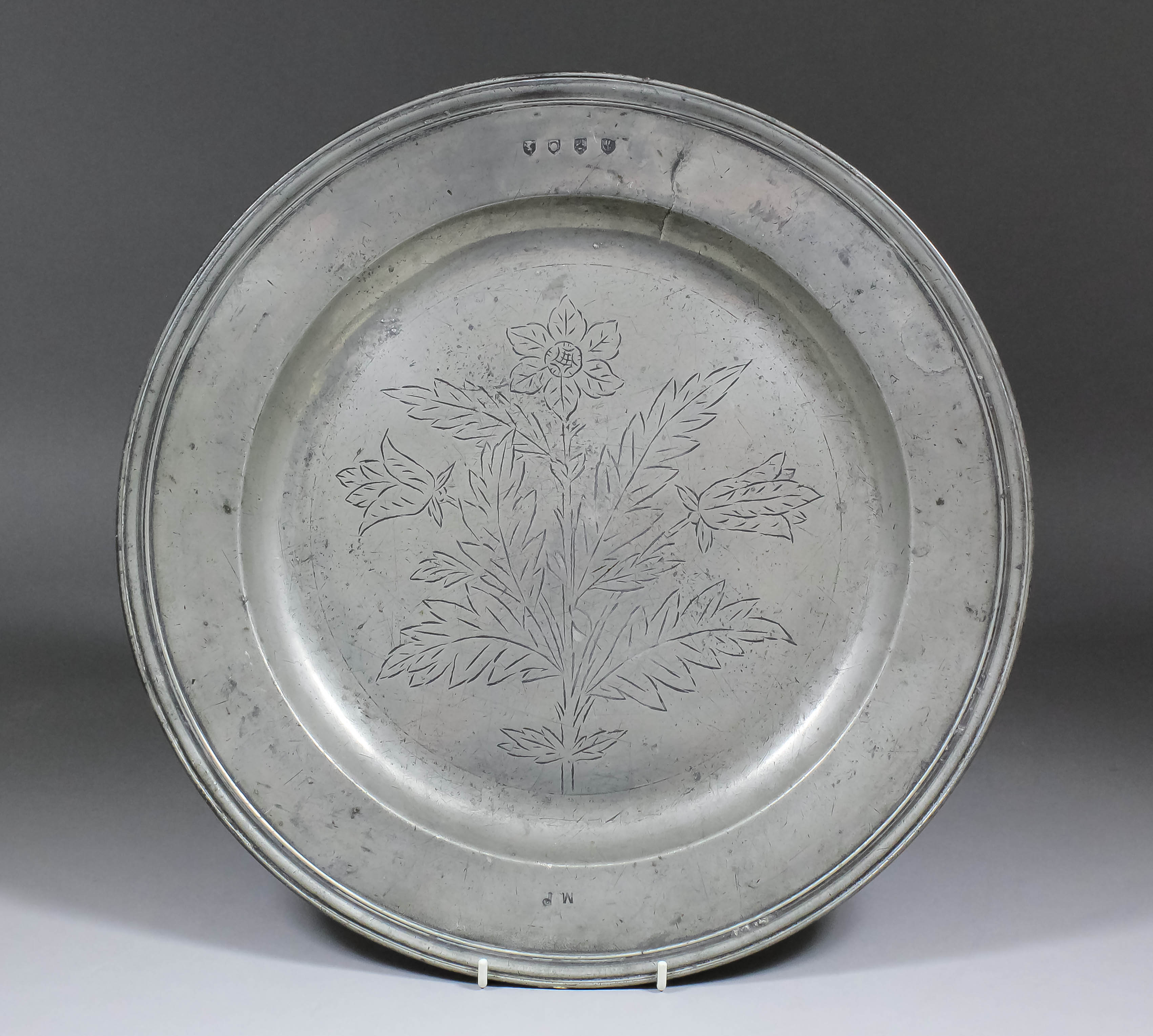 A 17th Century pewter dish, the centre with wrigglework decoration of a flower in full bloom with