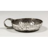 An 18th Century French silver circular taste-vin, the bowl with punched decoration of fruiting vines