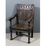 An old oak armchair, the back carved with scroll leaf and stylised floral ornament, on turned legs