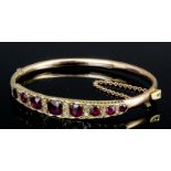 A late Victorian gold coloured metal mounted garnet and rose diamond set stiff pattern bracelet, the