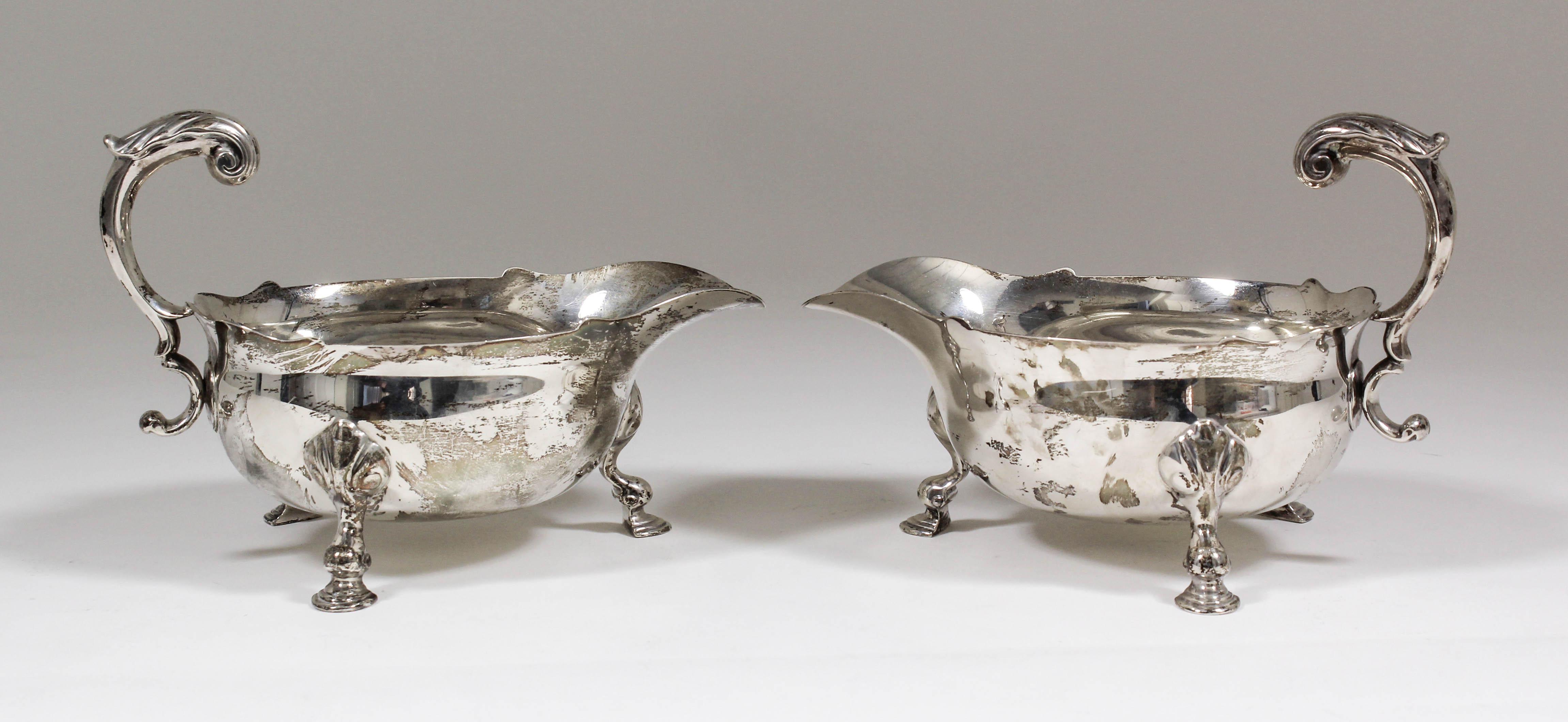 A pair of Elizabeth II silver sauce boats of large proportions with shaped rims, double C-scroll