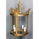 A lacquered brass and glass cylindrical four light hall lantern on scroll supports, the uprights