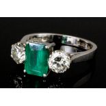 A modern platinum mounted emerald and diamond three stone ring, the rectangular cut emerald