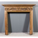 A 20th Century stripped pine fire surround with moulded and carved cornice, the frieze carved in