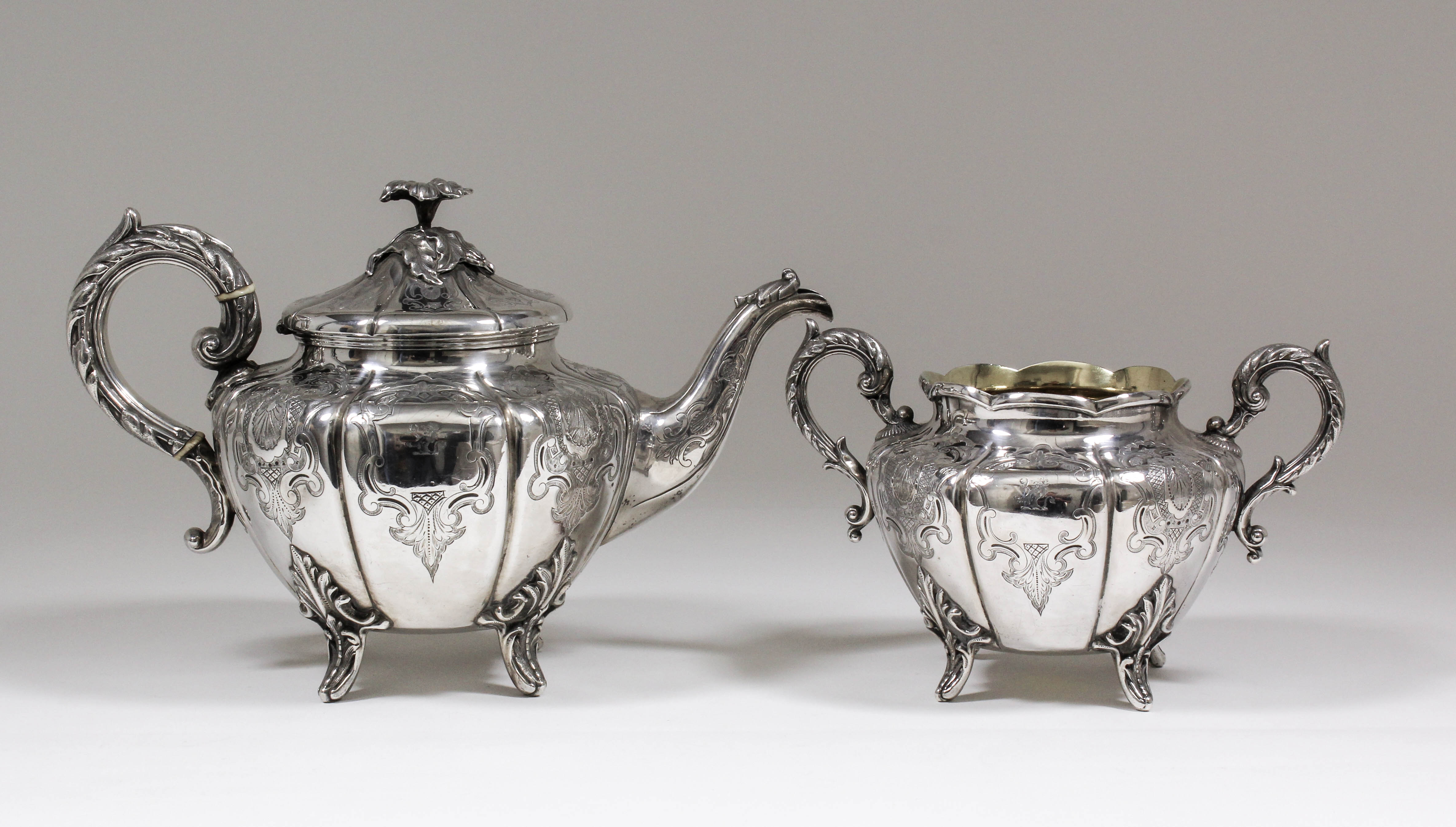 A Victorian silver circular teapot of bulbous panelled form, the whole engraved with scroll and