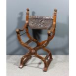 An early 20th Century walnut framed X-pattern armchair with fluted uprights to back with carved