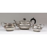 A George V silver three piece tea service of Georgian design with cast shell, gadroon and leaf