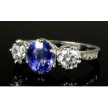 A modern silvery coloured metal mounted sapphire and diamond three stone ring, the central