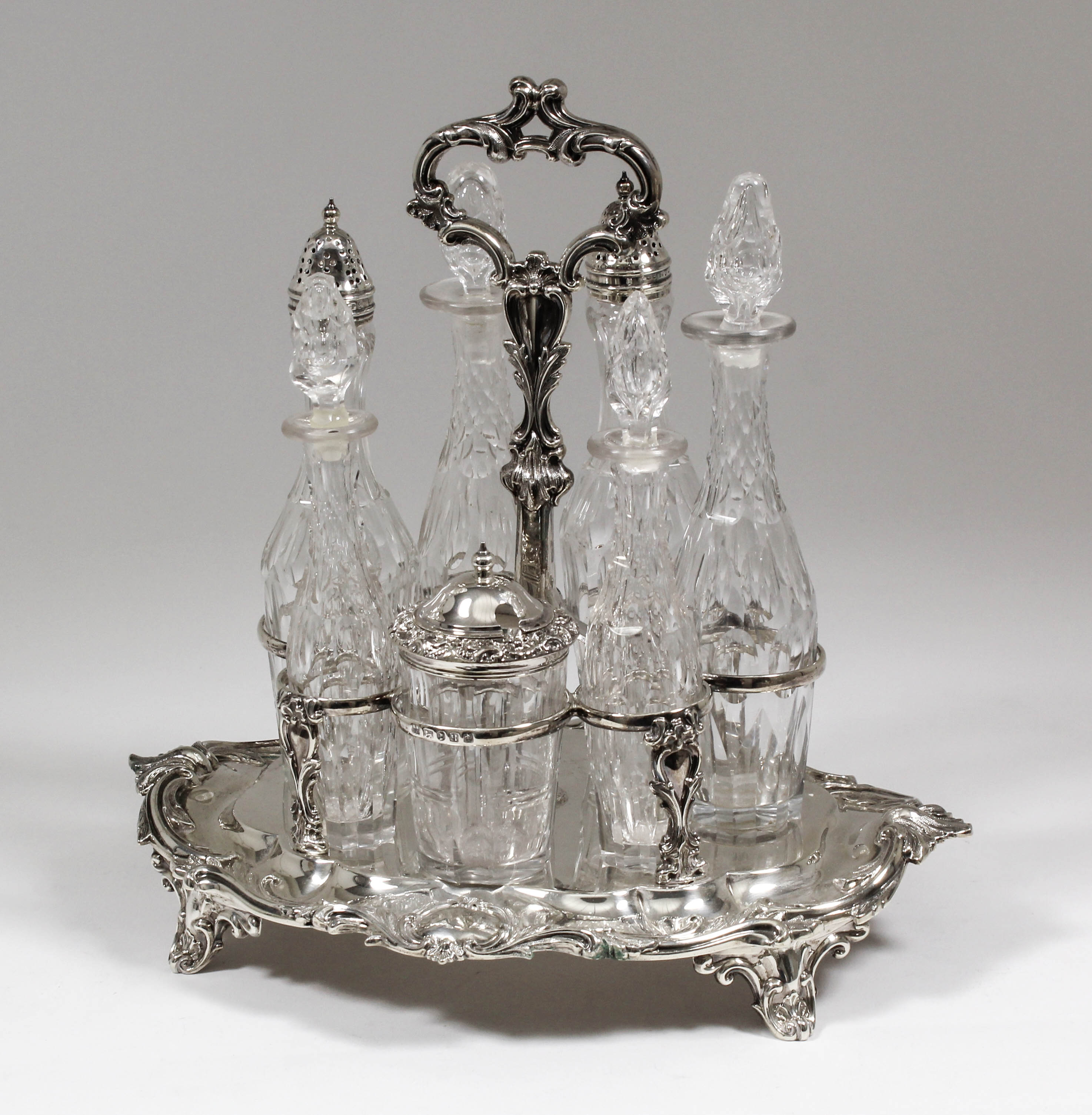 A Victorian silver oval seven division cruet stand with cast leaf scroll capped loop centre