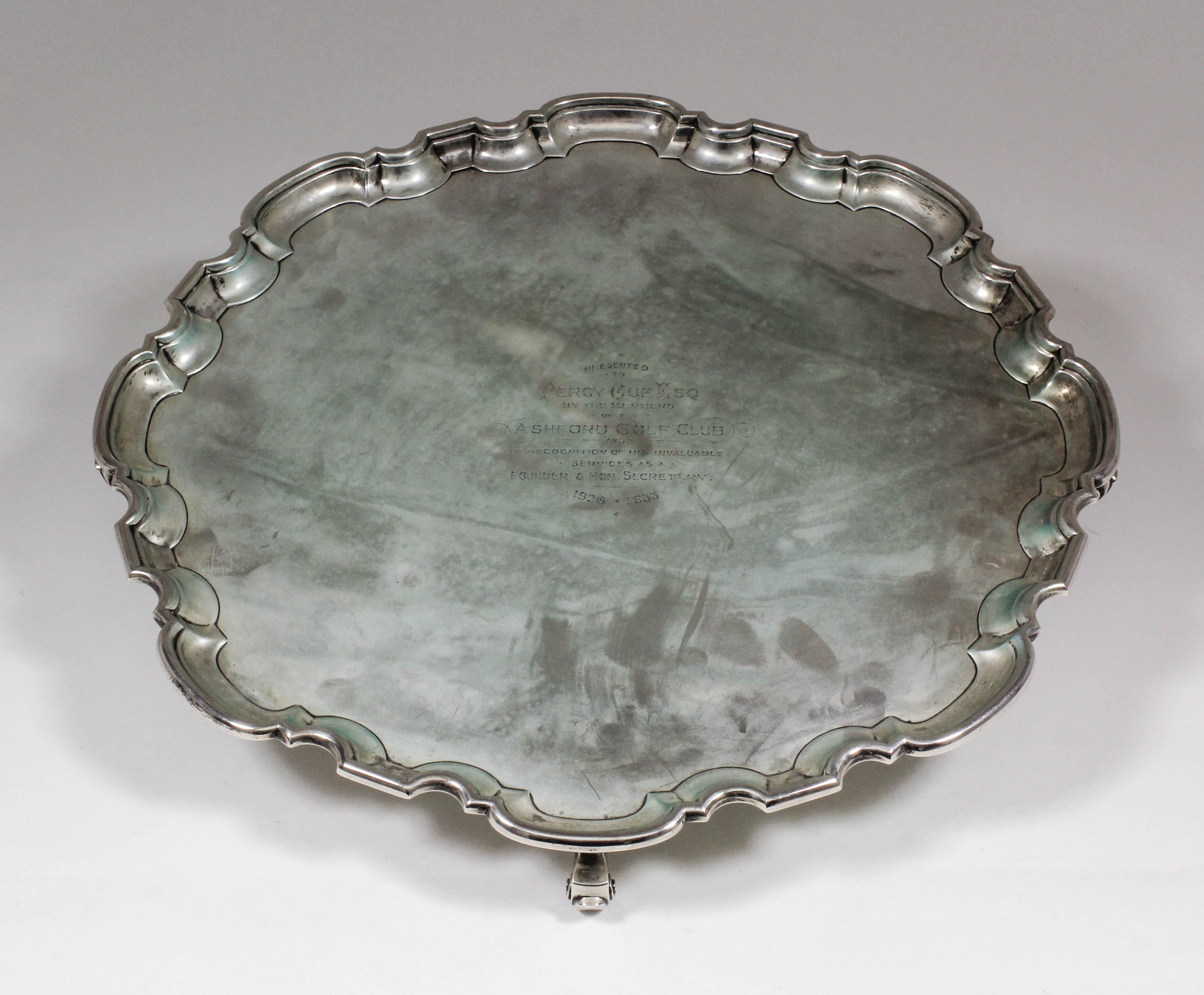 A George V silver circular salver of Georgian design with moulded piecrust rim, on four scroll feet,