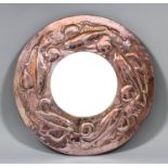 An early 20th Century Newlyn copper circular mirror, hammered in relief with a frieze of four