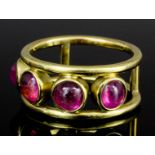 A modern 18ct gold mounted pink topaz set ring, the twin bands with four collet set cabochon cut