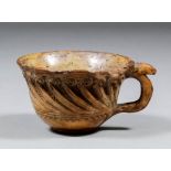 An interesting polished terracotta cup, the central band with a carved wave design, 2ins diameter