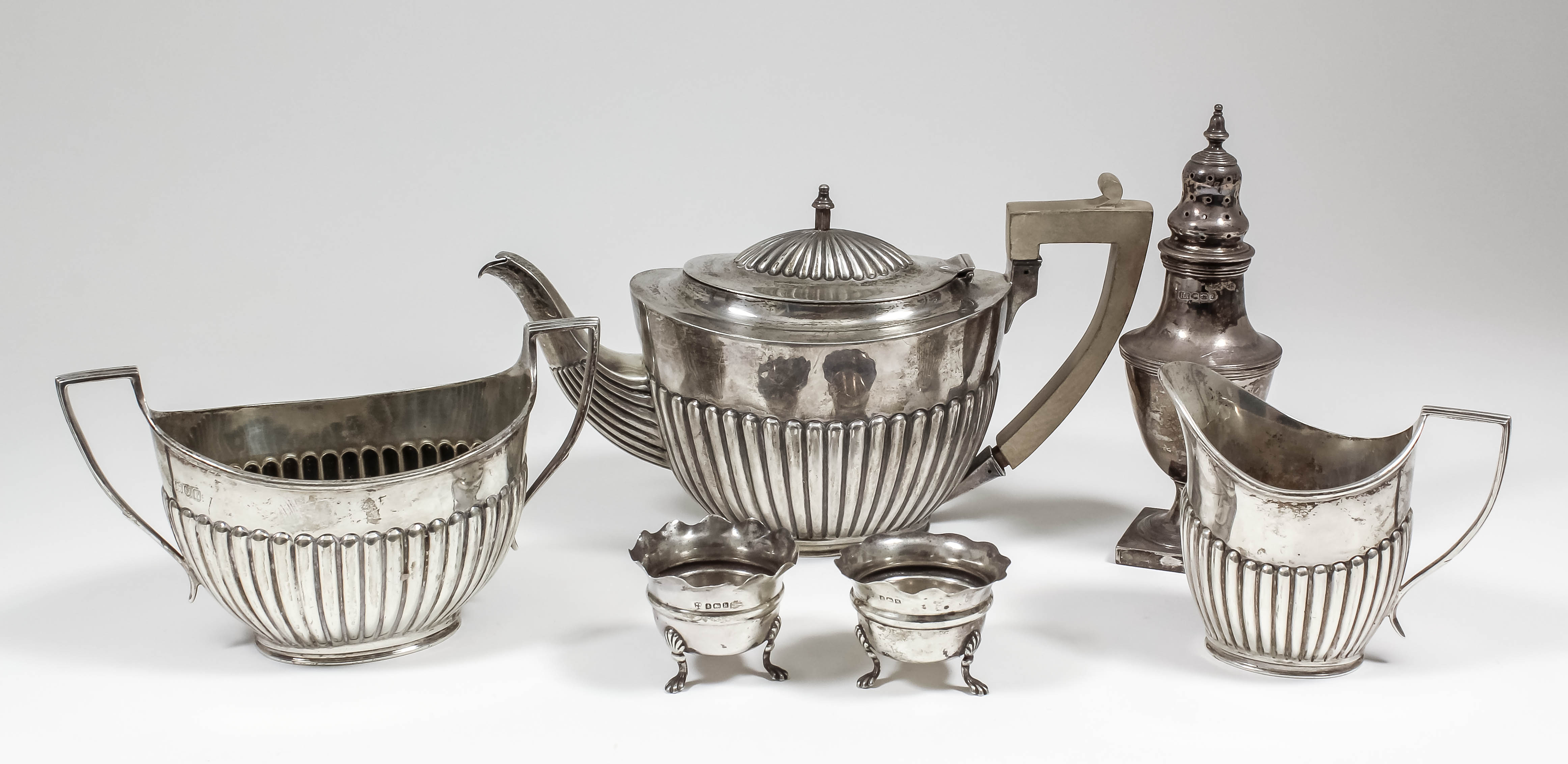 An Edward VII silver oval three piece tea service with part reeded bodies and angular loop