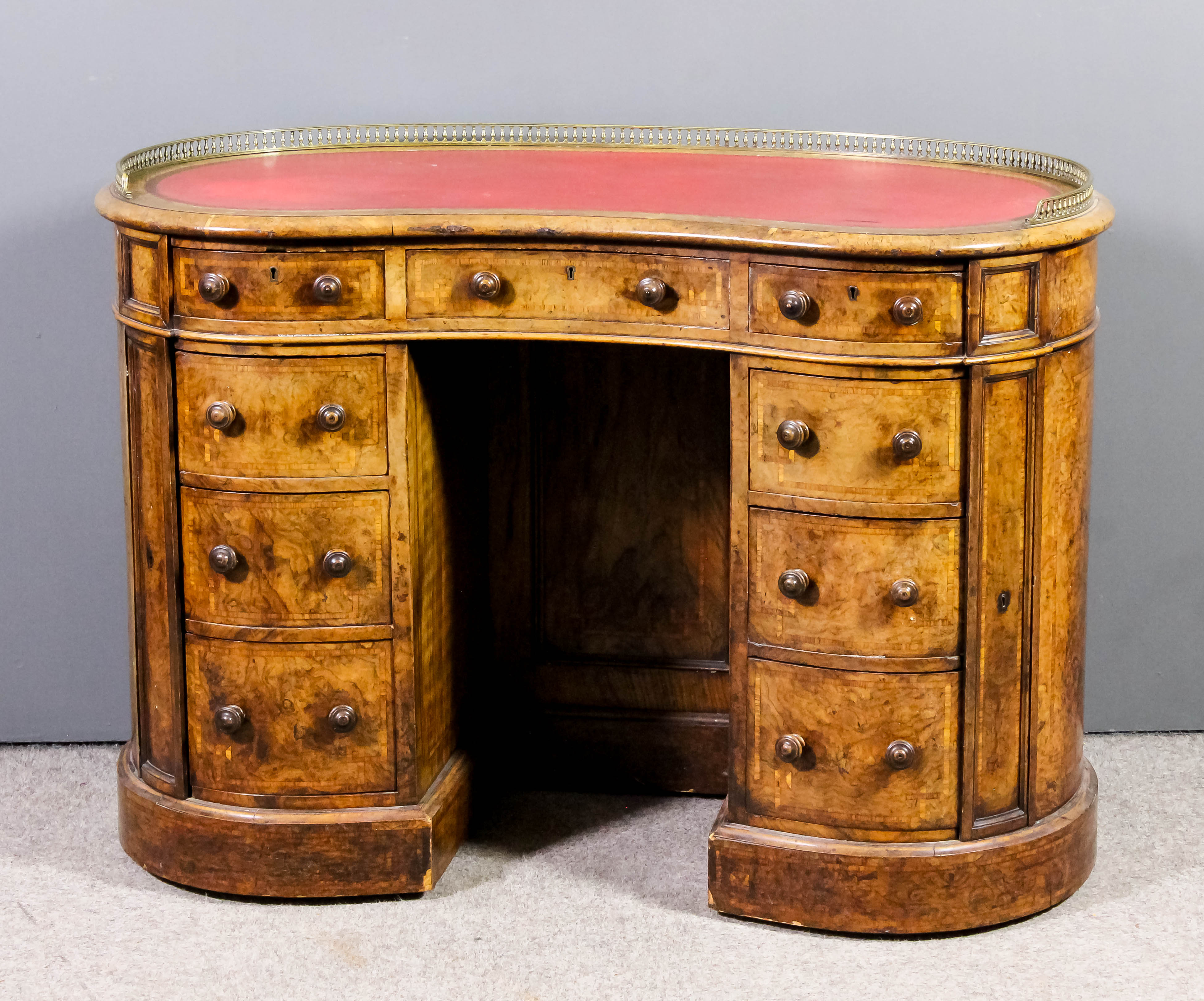 A Victorian lady's figured walnut kidney shaped kneehole desk with gilt brass gallery and red