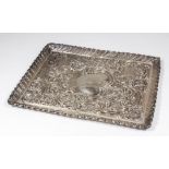 A late Victorian silver rectangular dressing table tray, the centre boldly embossed and chased