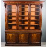 An early Victorian figured mahogany three door bookcase, the upper part with moulded cornice, fitted