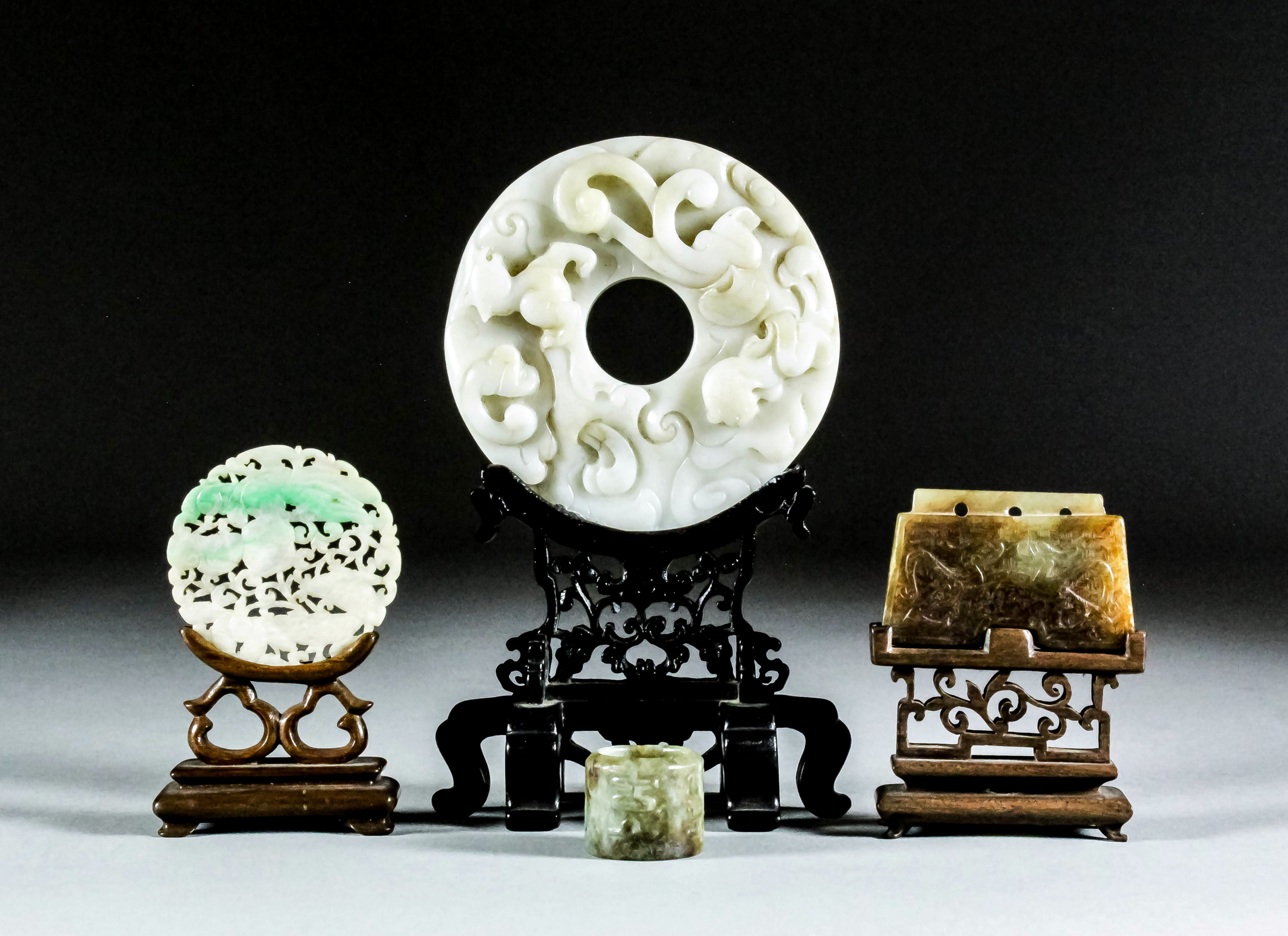 A Chinese green and white jadeite circular disc, pierced and carved with lotus pods and bird