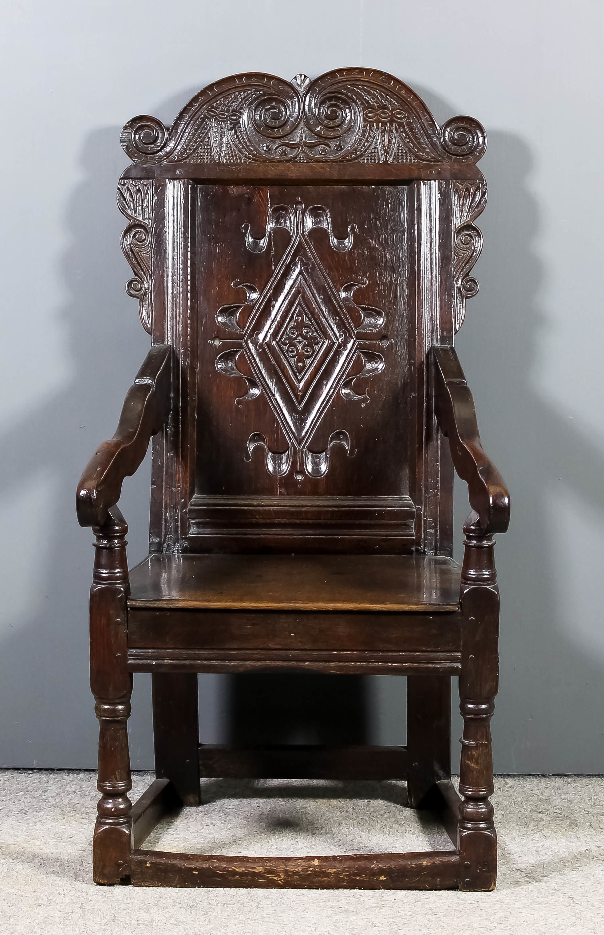 A good 17th Century panelled oak "Wainscot" armchair, with bold shaped and carved scroll pattern