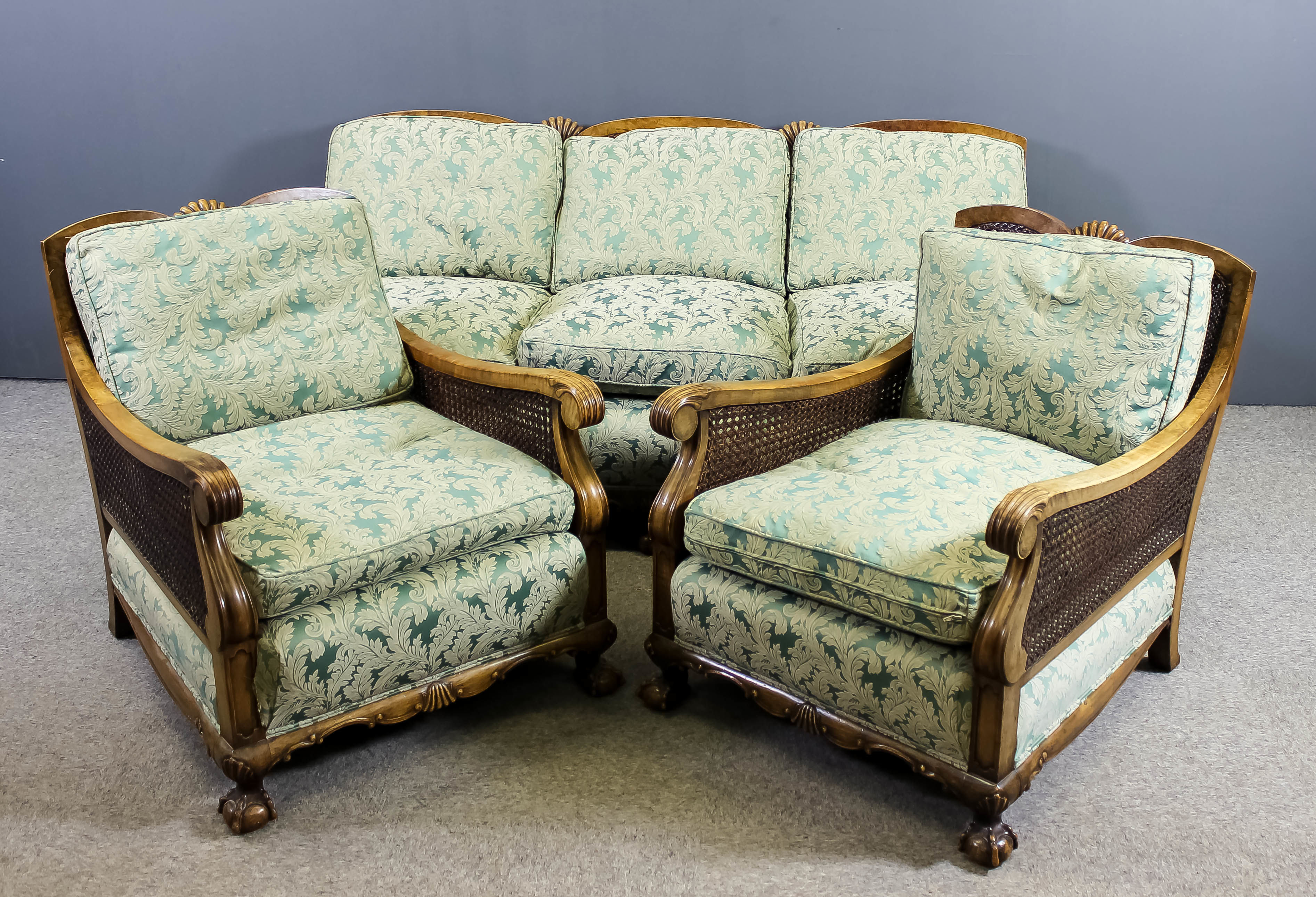 A 1930's walnut framed three piece Bergere suite, the arched backs with solid splats and reeded