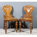 A pair of early Victorian oak hall chairs, the shaped backs inset with painted crest to shield