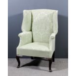 A mahogany wing back easy chair of Georgian design upholstered in green and ivory floral patterned