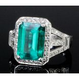 A modern platinum mounted emerald and diamond ring, the oblong emerald cut stone of approximately