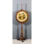 A Victorian walnut pole screen with circular panel, with moulded, fretted and carved scroll frame,