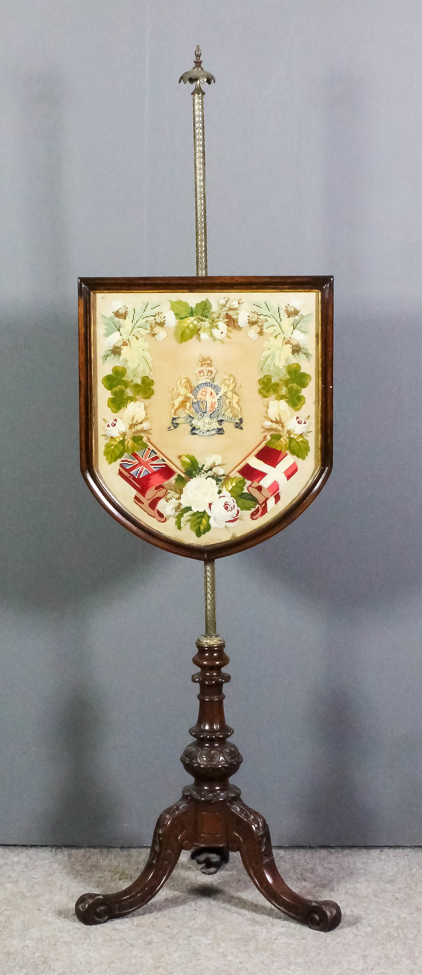 A late Victorian walnut framed pole screen with shield shaped needlework panel embroidered with