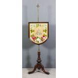 A late Victorian walnut framed pole screen with shield shaped needlework panel embroidered with