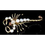 A modern 9ct gold moonstone and garnet set scorpion pattern brooch, the eyes and tail set with small