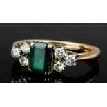 A 1960s gold coloured metal mounted emerald and diamond ring, the central oblong cut emerald