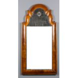 A walnut wall mirror of early 18th Century design, the deep rectangular cushion frame with arcaded