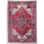 A Heriz carpet woven in colours, with a bold central cross and lozenge pattern medallion, with