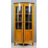 A Continental fruitwood and ebonised bow-front corner cupboard in the "Biedermeier" style, fitted