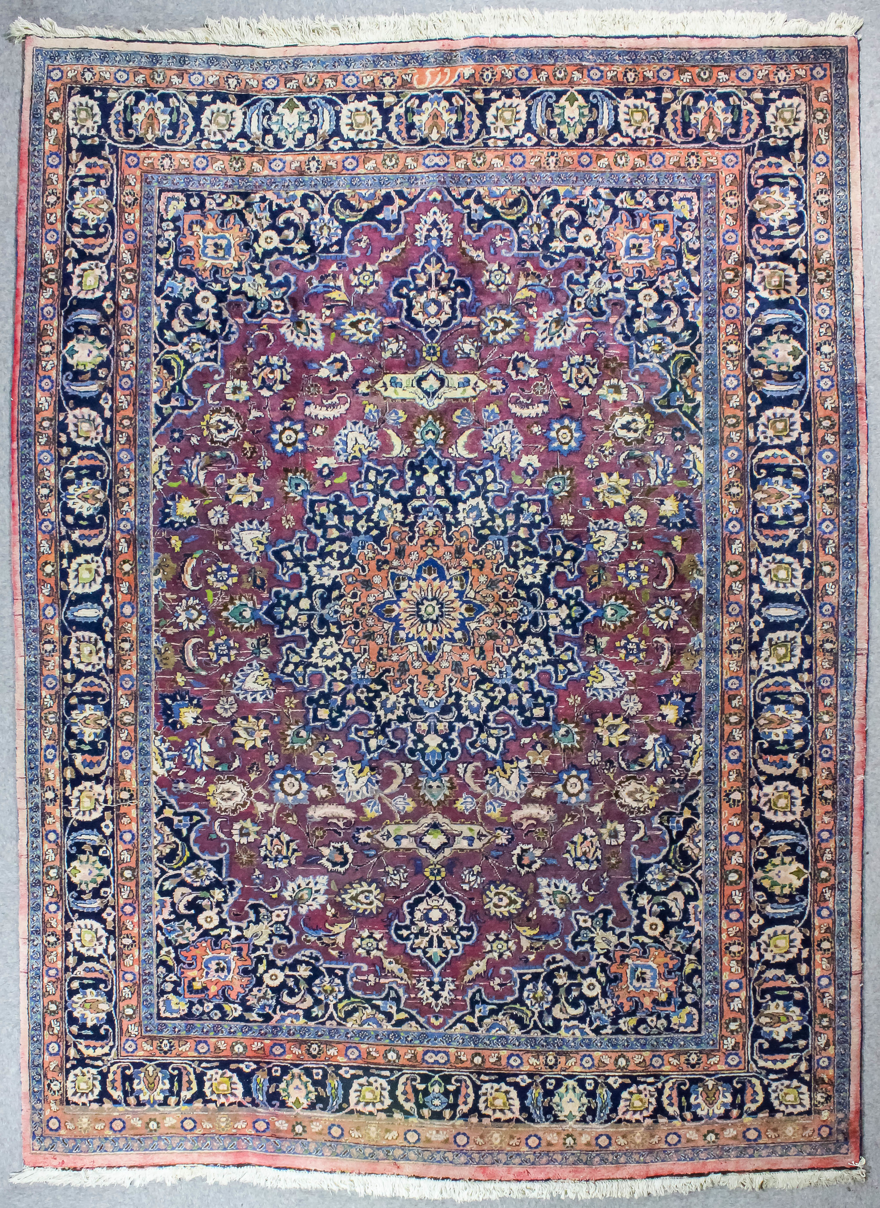 A Meshad carpet woven in colours, with a bold circular floral filled medallion and conforming