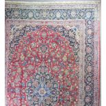 A large Kashan carpet woven in colours, central leaf and floral filled medallion and conforming