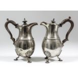 Two Edward VII silver baluster-shaped hot water pots with shaped rims, moulded girdles, wooden