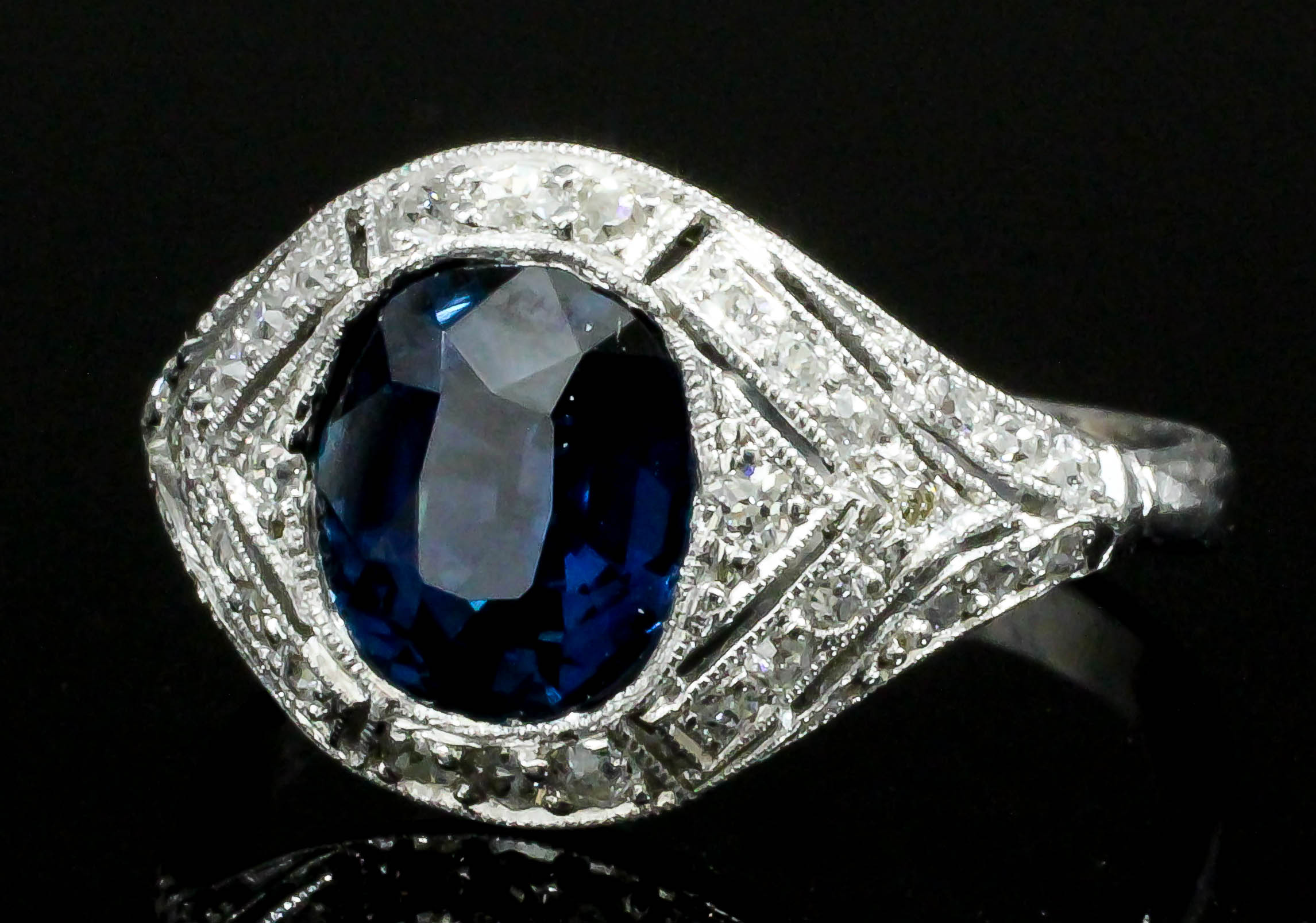A silvery coloured metal mounted sapphire and diamond ring in the "Art Deco" manner, the oval cut