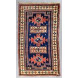 A Kazak Karachop rug woven in colours with three bold cross motifs, interspersed by two