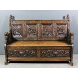 A 19th Century carved oak settle, the four panel back carved with figures in an inn, with leaf
