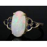 A 1960s gold coloured metal mounted opal and sapphire ring, the oval cut opal approximately 3ct