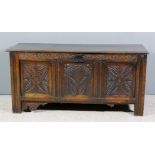 A 17th Century panelled oak coffer with plain lid, the front with moulded rails later carved with