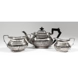 An Edward VII silver oval three piece tea service with gadroon mounts, part reeded bodies and