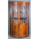 A late George III mahogany bow-front corner cupboard of large proportions, the upper part with
